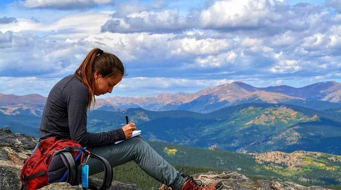 A hiker resting on a summit above Idaho Springs, the Front Range behind